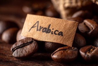 Arabica kávészemek közelről, papír címkével – Caffè Gioia Arabica kávék