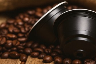 Dolce Gusto kompatibilis kávékapszulák pörkölt kávészemekkel, rusztikus fa felületen – Caffè Gioia kapszulák